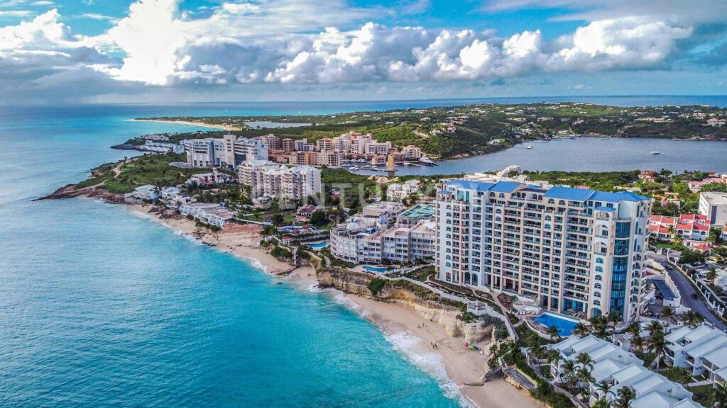 coconut-palms-P9VSUQF-2 - Wei Landgraf Aerial view of a coastal resort with white high-rise buildings along a sandy beach and turquoise sea nearby.